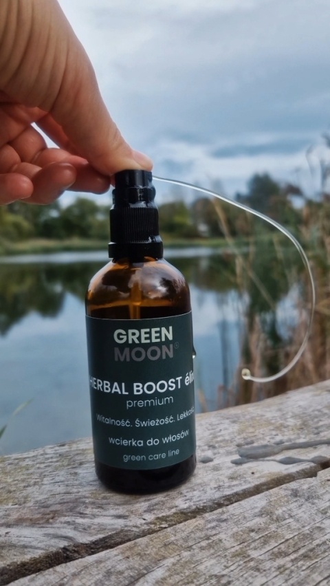 Naturalna wcierka HERBAL BOOST élixir premium GREEN MOON® na tle łąki i błękitnego nieba