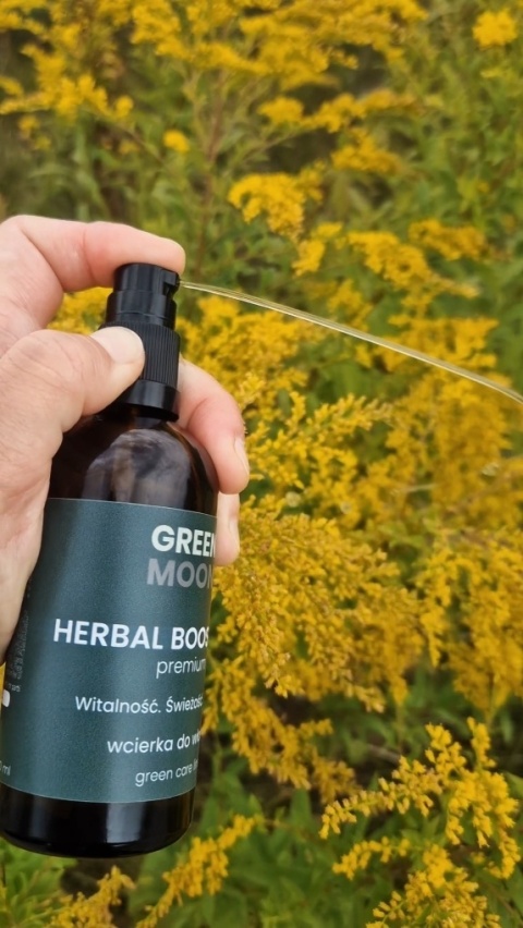 Naturalna wcierka HERBAL BOOST élixir premium GREEN MOON® na tle łąki i błękitnego nieba